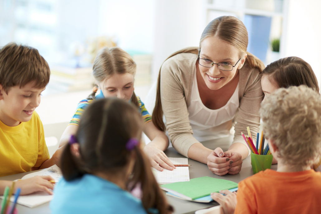 Schoolkids and their teacher talking at lesson